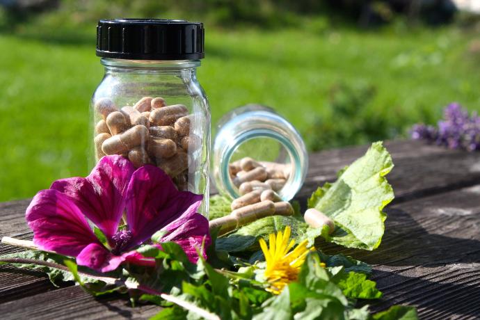 Naturpflanzenextrakte Kapseln in Glasflaeschchen dekoriert mit kraeutern, aufnahme im freien
